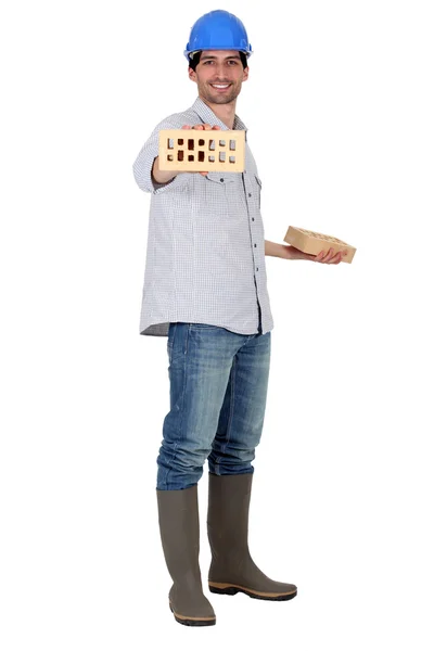 Man wearing a safety hat and showing a brick — Stock Photo, Image