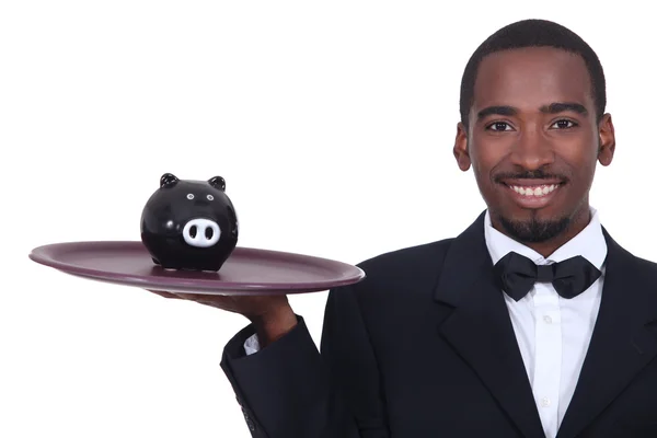 Waiter holding a piggy bank on his tray — Stock Photo, Image
