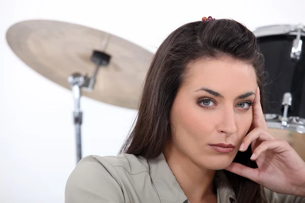 Mooie brunette met drums op achtergrond — Stockfoto