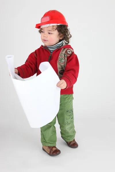 Μικρό αγόρι ντυμένος ως οικοδόμος κρατώντας σχέδια — Φωτογραφία Αρχείου
