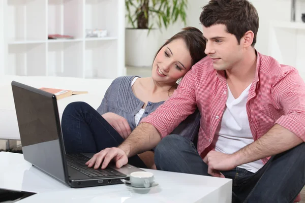 Пара расслабляется дома перед своим ноутбуком — стоковое фото