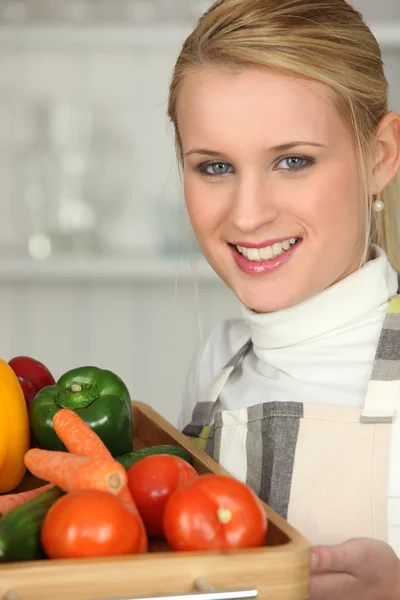 Jonge vrouw met een lade van verse groenten — Stockfoto