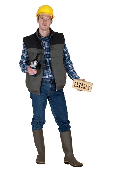 Mason holding brick and angle grinder — Stock Photo, Image