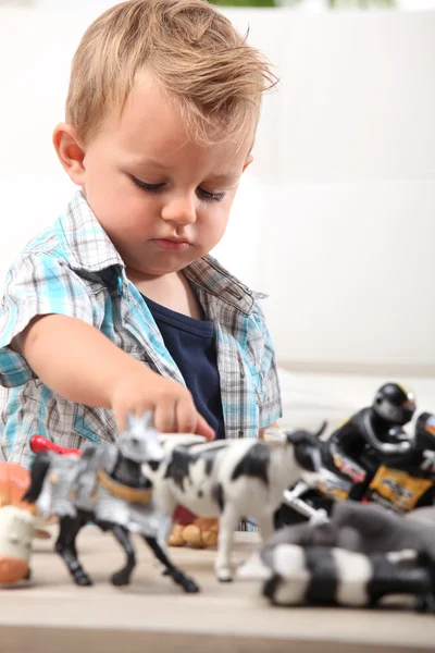 Young boy playing with a selection of toy figurines and animals — Stock Photo, Image