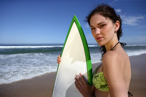 Brunette stond op strand met surfboard — Stockfoto