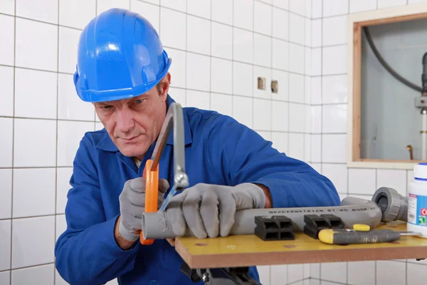Bauarbeiter sägt an einem Rohr — Stockfoto