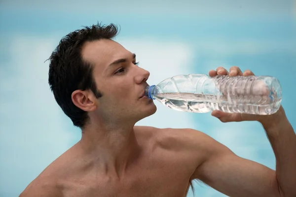 Мужчина без рубашки пьет из бутылки с водой — стоковое фото