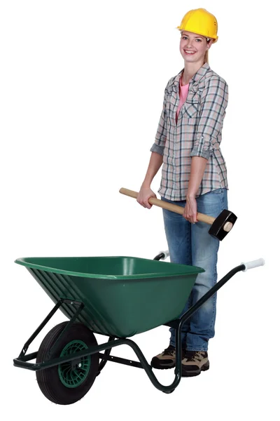 Tradeswoman placing a mallet in a wheelbarrow — Stock Photo, Image