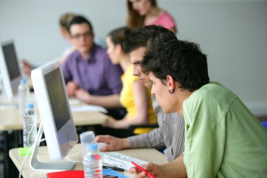 Young men using a computer in the classroom clipart