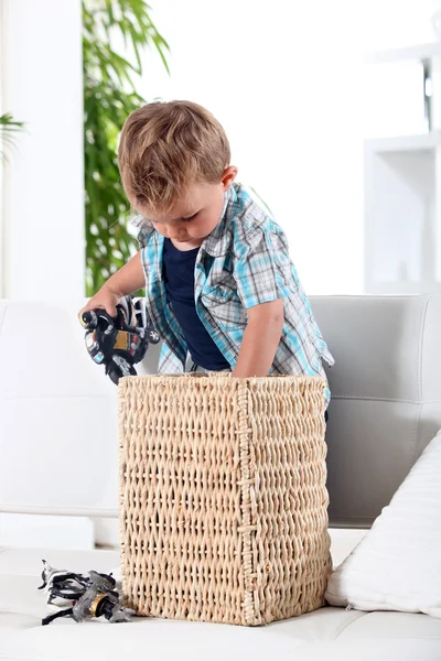Kleine jongen zijn speelgoed in een mand opruimen — Stockfoto