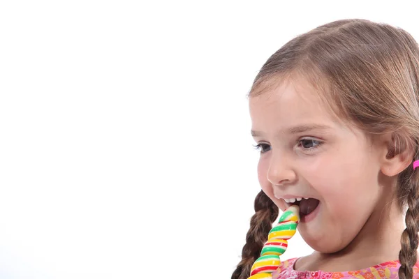 Kleines Mädchen aß ein Bonbon, sah amüsiert und verschmitzt aus — Stockfoto