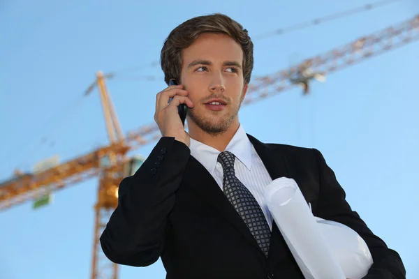 Architect on site with plans and cellphone — Stock Photo, Image