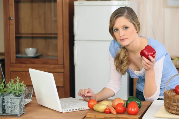 Mulher cozinhar ao lado do laptop — Fotografia de Stock