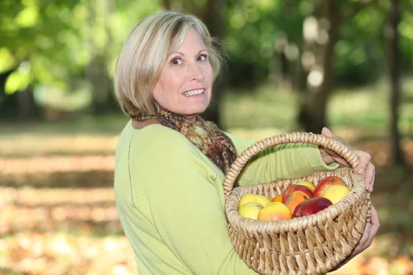 Rijpe blonde vrouw in orchard — Stockfoto