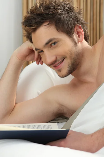 Young man reading in bed Stock Picture