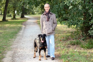 Senior man walking his dog in the woods clipart