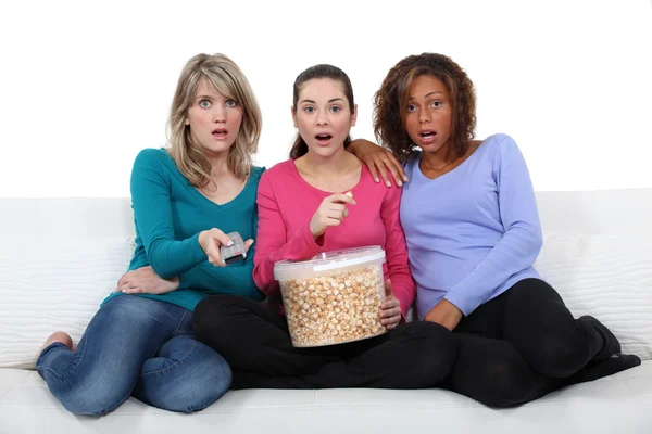 Três amigos assistindo televisão e comendo pipocas — Fotografia de Stock