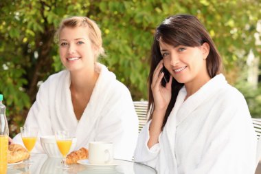 Young women having breakfast on the patio clipart