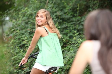 Two teenage girls on bike ride clipart