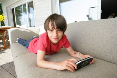 Little boy laying on sofa with hand-held video game clipart