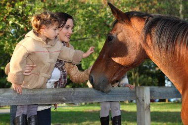 Mother and daughter next to horse clipart