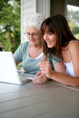 Mother and daughter using laptop clipart