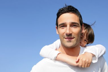 Young boy riding piggy-back on his father's back clipart