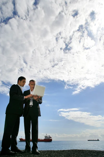 商人使用一台笔记本电脑针对蓬松的云蓝蓝的天空 — 图库照片