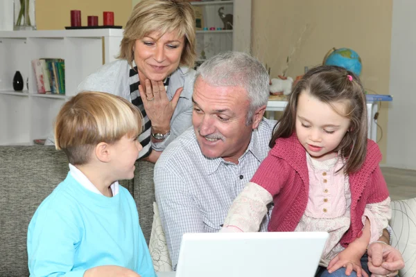 Pensioners with grandchildren using computer — Stock Photo, Image