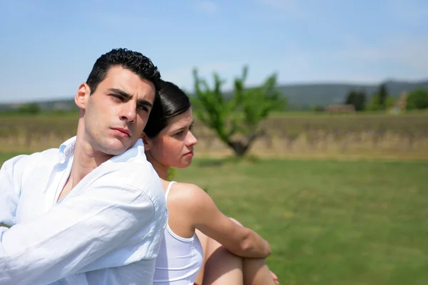 Casal sentado de costas para trás em um campo — Fotografia de Stock