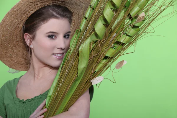 Woman in hat holding large leaves — Stock Photo, Image