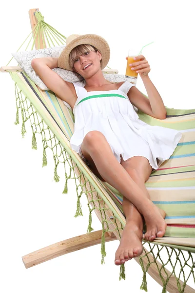 Блондинка відпочиває і п'є в гамаку — стокове фото