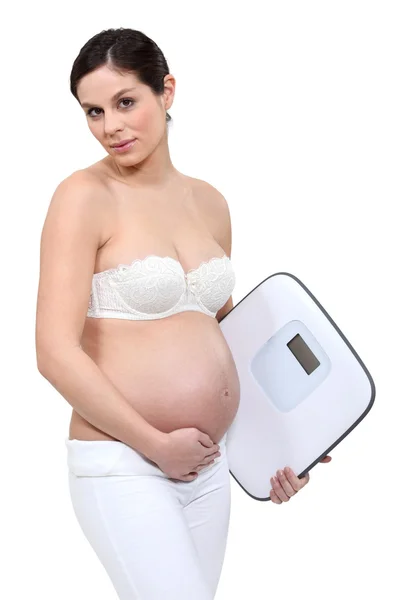 Eine schwangere Frau mit einer Waage. — Stockfoto