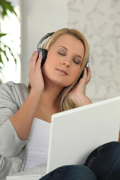 Mulher loira ouvindo música através de laptop — Fotografia de Stock