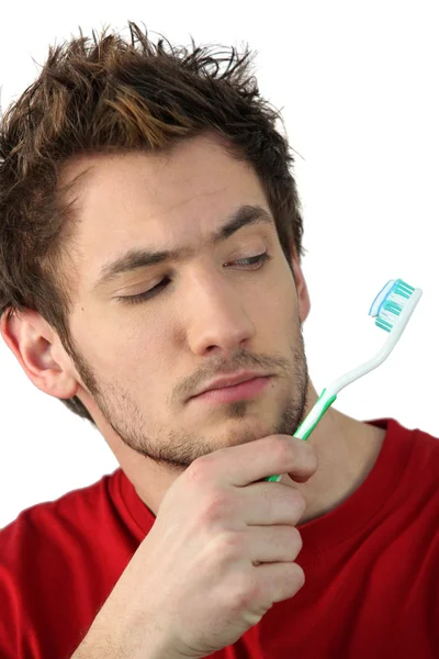 Young man looking at his toothbrush — Stock Photo, Image
