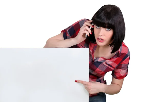 Woman holding blank message board and using telephone — Stock Photo, Image