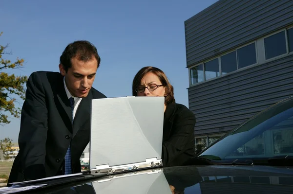 Par med sin laptop på sin bil — Stockfoto