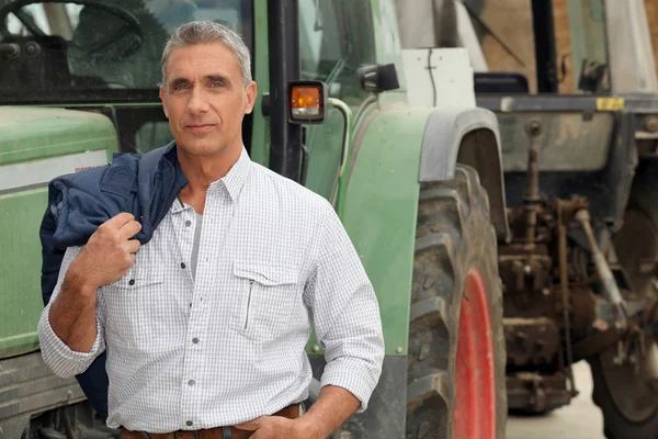 Farmář pózuje před jeho traktor — Stock fotografie