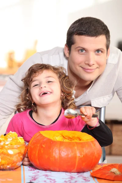 Un padre e la sua bambina ridono e mangiano una zucca — Foto Stock