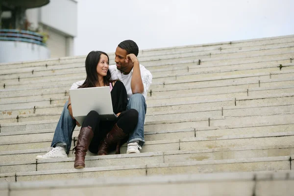 Young sitting on steps of stairs with laptop — Stock Photo, Image