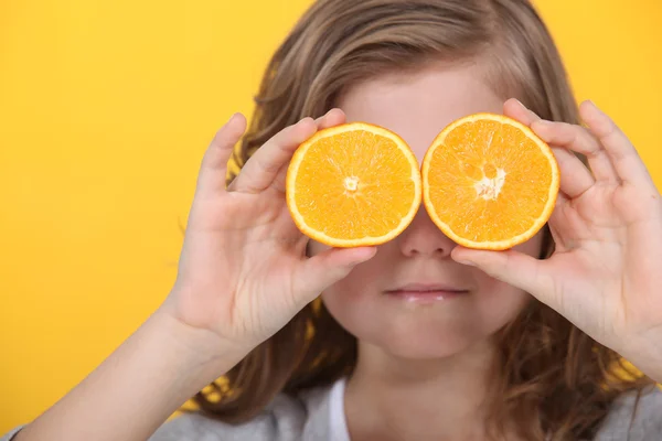 Niña cubriendo los ojos con rodajas de naranja — Foto de Stock