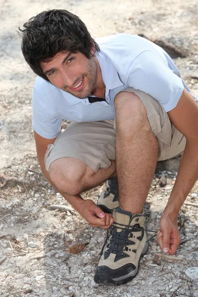 Молодой человек шнурует свои ботинки — стоковое фото