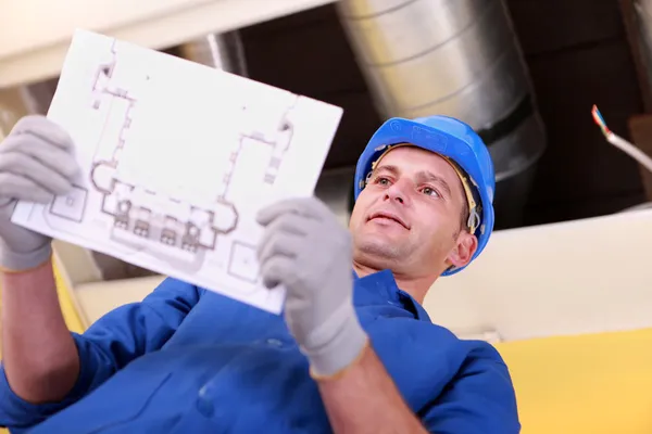 Man looking at plans for a heating installation — Stock Photo, Image