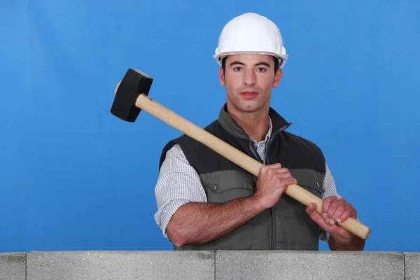 Homem levantando martelo ao lado da parede — Fotografia de Stock