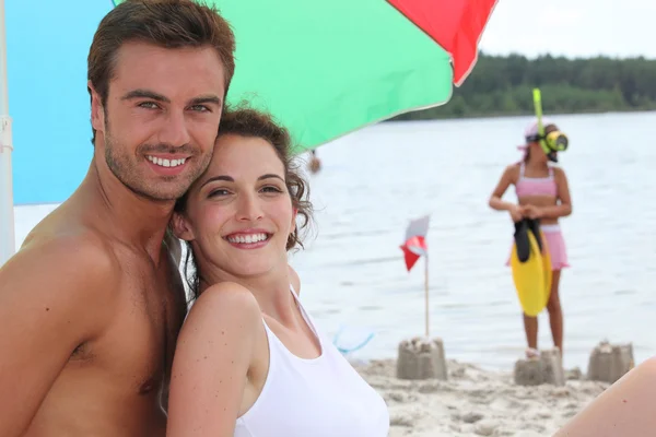 Couple sur une plage de sable avec fille en arrière-plan — Photo