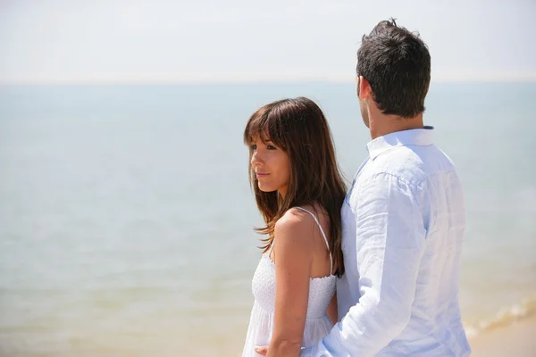 Jeune couple portant du blanc à la plage — Photo
