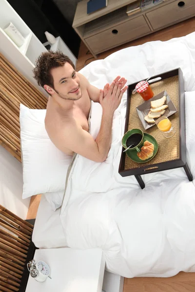 Ο άνθρωπος τρώει πρωινό στο κρεβάτι — Φωτογραφία Αρχείου