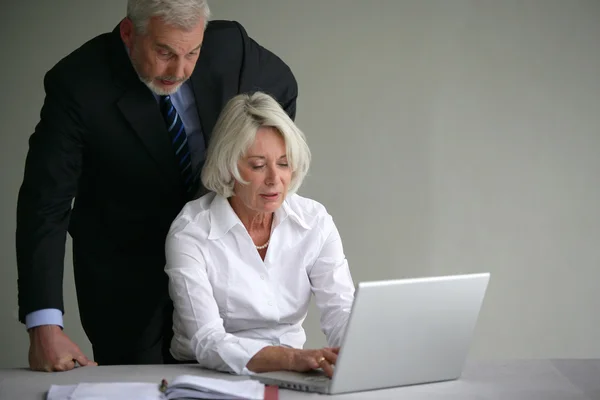 Senior couple in suit in front of a laptop computer — Stock Photo, Image