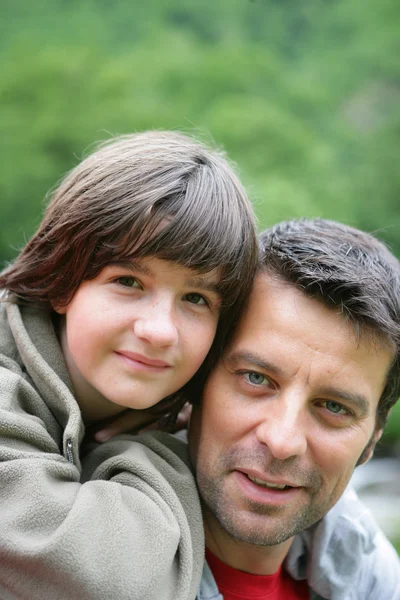 Child riding piggyback on his father's back — Stock Photo, Image