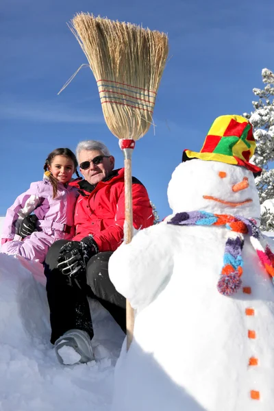 Father and daughter stood with snowman — Stock Photo, Image